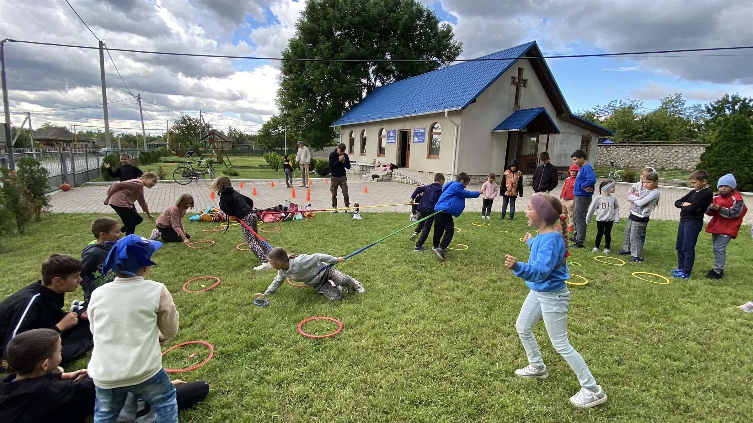 Kinder spielen auf der Wiese vor dem Gemeindehaus.