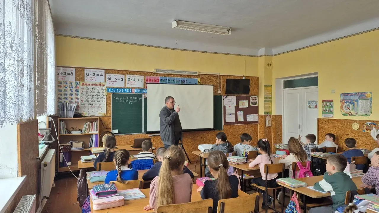 Eine Schulklasse im Unterricht, der Lehrer steht vorn an der Tafel.