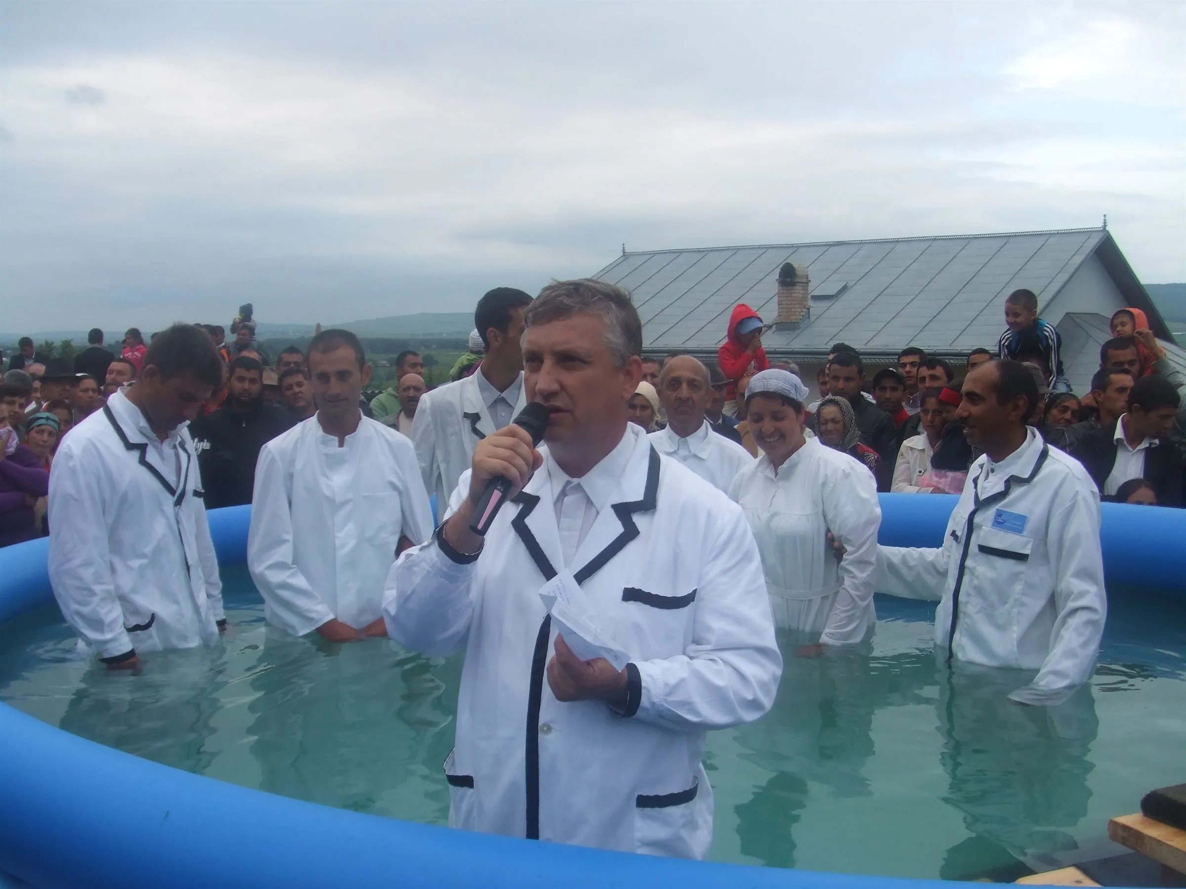 Eine Taufe unter freiem Himmel, mehrere Täuflinge stehen im Wasser.