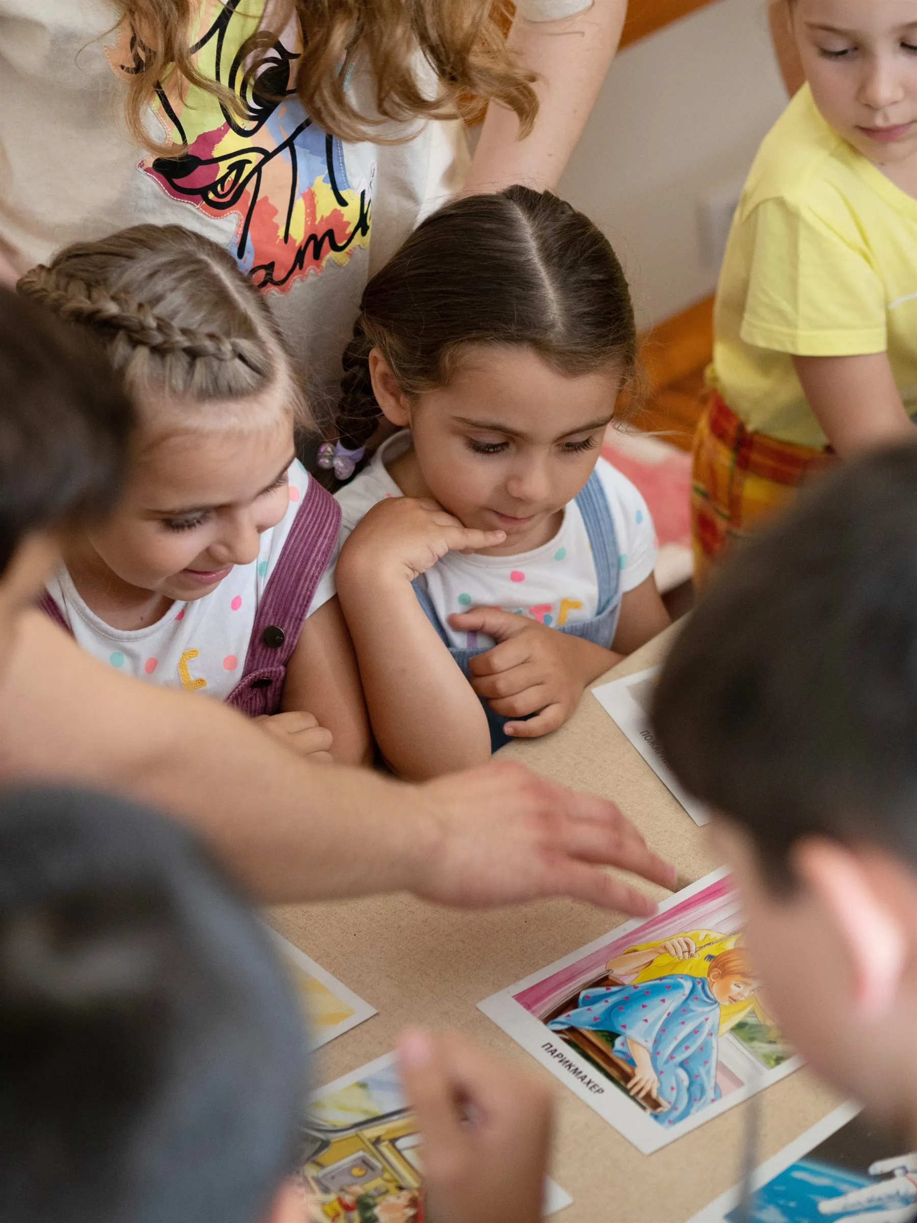 Kinder beugen sich über Bildkarten, die auf dem Tisch ausgelegt sind.