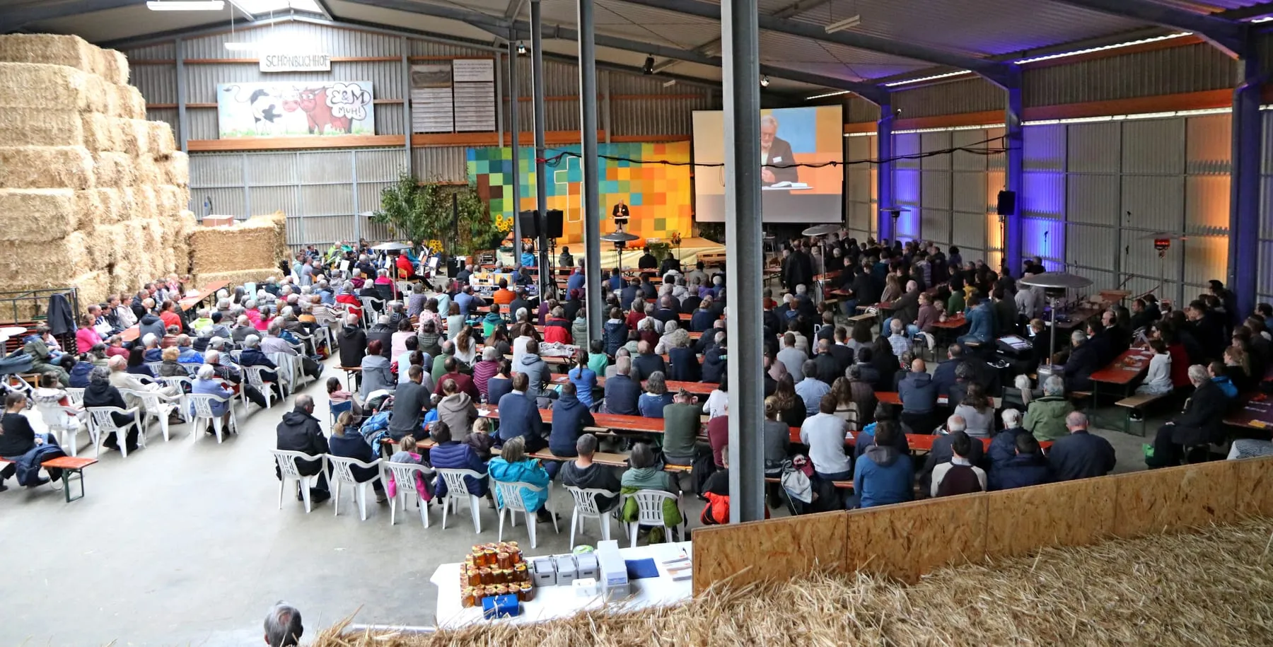 Missionstag im Schönbuchhof: die Halle ist bis in die hinteren Reihen besetzt, vorne spricht jemand auf der Bühne.