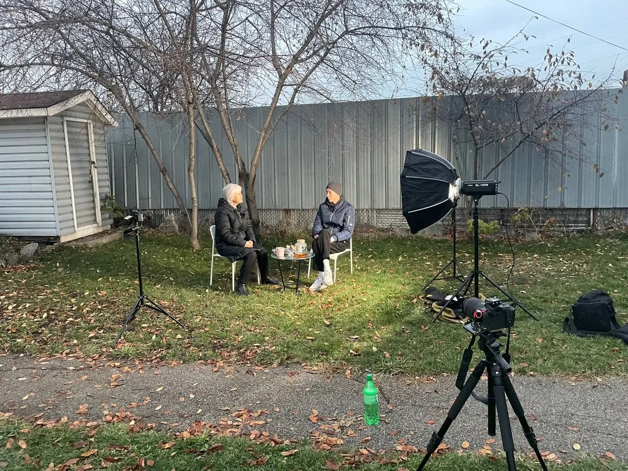 Ein Filmteam nimmt im Freien ein Gespräch auf, Kamera und Leuchte stehen bereit.
