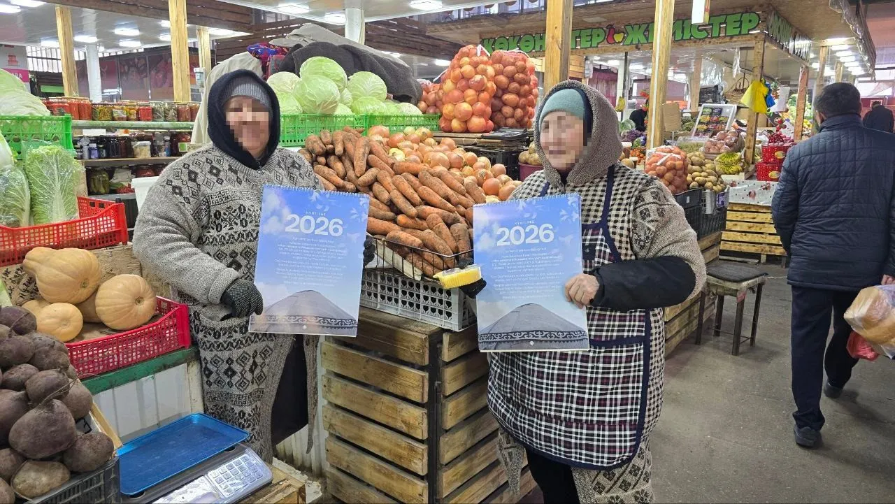 Zwei Frauen auf dem Markt halten den christlichen Wandkalender in die Kamera.
